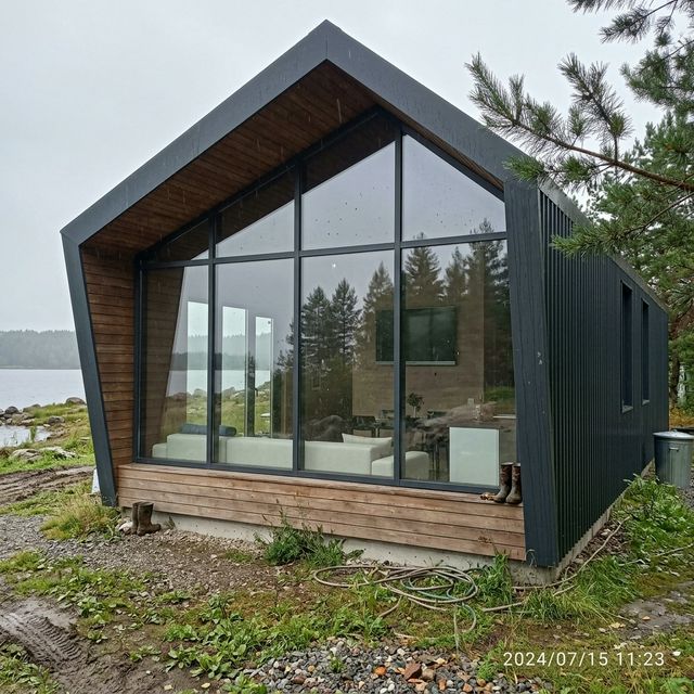 Casa prefabricada de acero con fachada panorámica junto a un lago